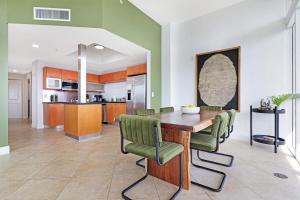 une cuisine et une salle à manger avec une table en bois et des chaises vertes dans l'établissement Roami at Sunny Isles, à Miami Beach