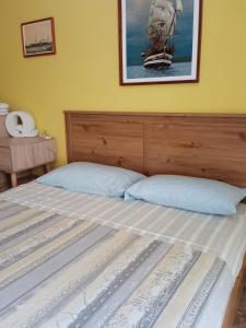 a bed with a wooden headboard and a picture of a ship at Piazza Ginnasio Affittacamere in Alghero