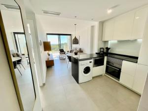 a kitchen with a washing machine and a dining room at Apartamento Sukha Vistas al Mar in Gran Alacant