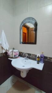 uma casa de banho com um lavatório branco e um espelho. em Flowered private room no Cairo