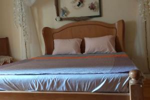 uma cama com uma cabeceira em madeira e 2 almofadas em Flowered private room no Cairo