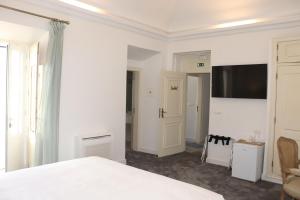 a bedroom with a bed and a tv on the wall at SOLAR DOS FRADES in Ferreira do Alentejo