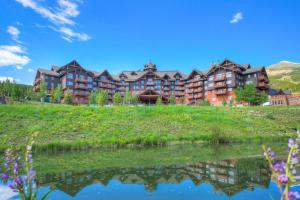 a large hotel on a hill next to a lake at One Ski Hill, A RockResort in Breckenridge