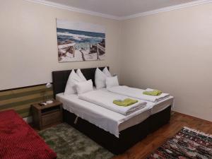 Schlafzimmer mit einem Bett mit weißer Bettwäsche und Kissen in der Unterkunft Arnika Vendégház in Hajdúszoboszló