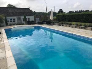 a large blue swimming pool in front of a house at Little Owl Barn in Marlborough