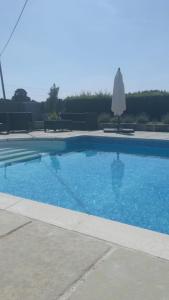 a blue swimming pool with an umbrella and a white umbrella at Little Owl Barn in Marlborough