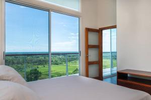 1 dormitorio con cama blanca y ventanas grandes en Casa Sol w/ Ocean View & Pool, en Paquita