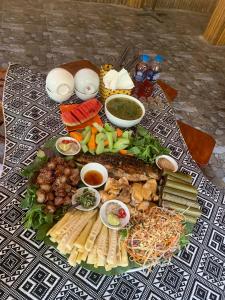 Mai Chau Home Holiday في ماي تشاو: طاولة مقدمة مع مجموعة متنوعة من الطعام على طاولة