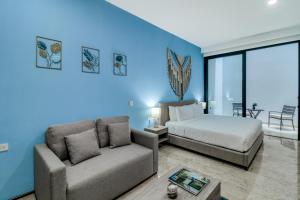 a bedroom with a bed and a couch at The Perfect Place, Unit 005 in Playa del Carmen