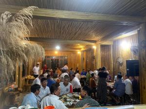 um grupo de pessoas sentadas em mesas em um restaurante em Mai Chau Home Holiday em Mai Châu