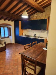 cocina con mesa de madera y armarios azules en Casa Fiore, en Passignano sul Trasimeno