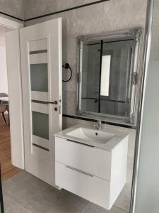 uma casa de banho com um lavatório branco e um espelho. em Vila Andrea em Oradea