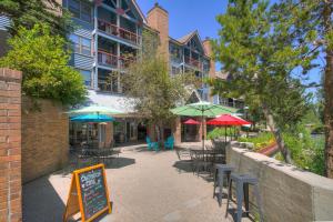 un patio avec des tables et des parasols en face d'un bâtiment dans l'établissement River Mountain Lodge by Breckenridge Hospitality, à Breckenridge