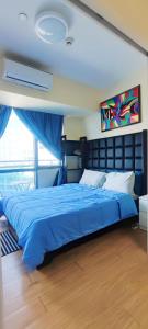 a bedroom with a blue bed with a blue blanket at Aveline Suites Executive City View ACQUA Private Residences near Rockwell Makati in Manila