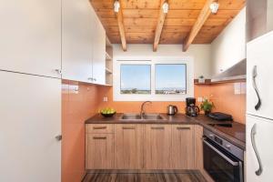 a kitchen with wooden cabinets and a sink and a window at Colorful House (Attic) in Kremasti
