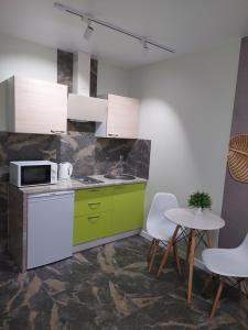 una cocina con armarios verdes, mesa y sillas en Сучасні апартаменти Палац Спорту, en Járkov