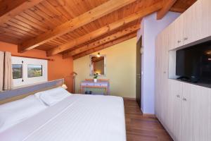 a bedroom with a white bed with a flat screen tv at Colorful House (Attic) in Kremasti