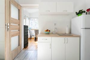 a kitchen with white cabinets and a wooden door at Kierunek Sopot Apartament WERANDA Haffnera 32 in Sopot