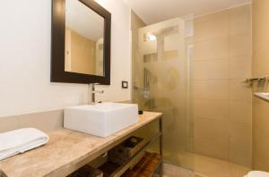 een badkamer met een witte wastafel en een douche bij Rivadavia Apartamentos in Ushuaia