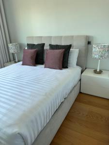 uma grande cama branca com 3 almofadas e 2 candeeiros em Leonor Seaview Apartment no Funchal