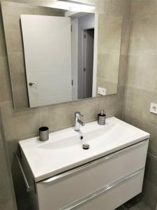 uma casa de banho com um lavatório branco e um espelho. em Apartamento céntrico en Palamós em Palamós