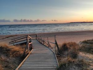 um calçadão de madeira que leva à praia ao pôr do sol em Strandskatan 102 em Halmstad