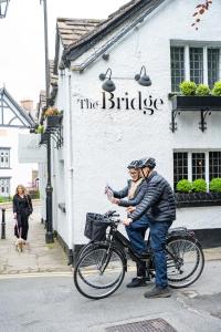 dos personas en una bicicleta delante de un edificio en The Bridge, en Macclesfield