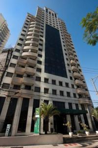 un edificio alto con una palmera delante de él en Studio Living Faria Lima, en São Paulo