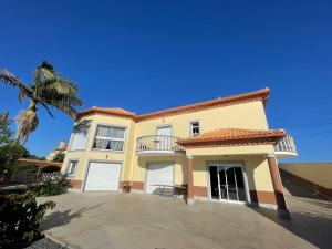 a large yellow house with white doors and a palm tree at Belle Vue in São Jorge