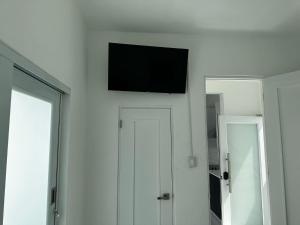 telewizor z płaskim ekranem wiszący na białej ścianie w obiekcie Gorgeous 1-Bedroom Beachside Suite w mieście San Juan