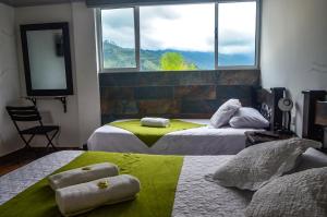 two beds in a room with a large window at Hotel La Floresta Salento in Salento