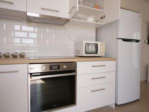 a white kitchen with a microwave and a refrigerator at Cozy corner Schinias beach house in Schinias