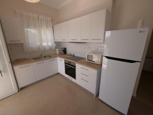 La cuisine est équipée de placards blancs et d'un réfrigérateur blanc. dans l'établissement Cozy corner Schinias beach house, à Schinias