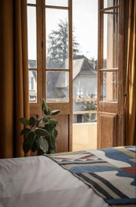 Un dormitorio con una cama y una ventana con una planta. en Venez Chez Vous - Villa Magnolia, en Annecy