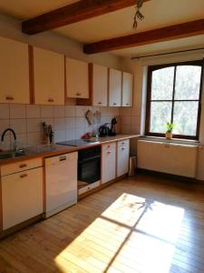 uma cozinha com armários brancos e uma grande janela em La sittelle des aguesses em Andenne