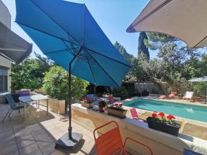 a blue umbrella sitting on a patio next to a swimming pool at Rougetomette in Nîmes