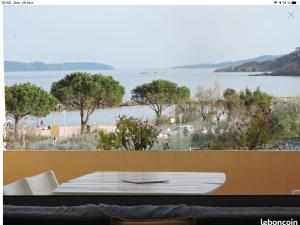 a table with a view of a beach and the ocean at Appartement pieds dans l’eau Vue Mer Bormes Les Mimosas in Bormes-les-Mimosas