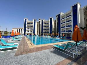 einem Pool mit Stühlen und Sonnenschirmen vor einem Gebäude in der Unterkunft Golden Jewel Ismailia Resort in Ismailia