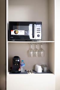 a kitchen shelf with a microwave and wine glasses at Apartamentos Centro in Albacete