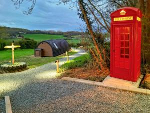 une cabine téléphonique rouge dans un jardin avec une croix dans l'établissement Lakeview Lodge- Uk40692, à Crowhurst