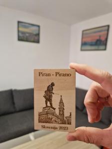 eine Hand, die eine Karte mit einem Bild einer Statue hält in der Unterkunft Apartment Niko in Piran
