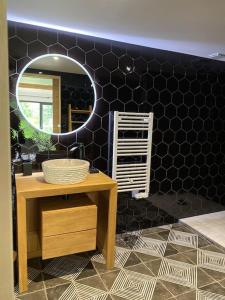 La salle de bains est pourvue d'un miroir sur un mur noir. dans l'établissement LE CLOS DAUPHINAIS Chez Laurette, à Quévert