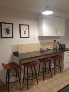 uma cozinha com um balcão e quatro bancos de bar em Lealt Falls House em Culnacnoc
