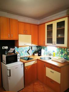 eine Küche mit Holzschränken, einer Spüle und einer Mikrowelle in der Unterkunft Apartment Niko in Piran