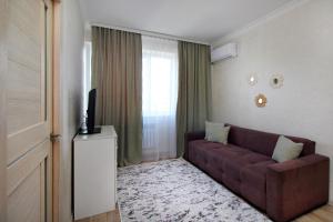 ein Wohnzimmer mit einem braunen Sofa und einem Fenster in der Unterkunft Уютная квартира в ЖК Адиет с видом на горы in Almaty