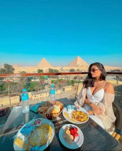 Una donna seduta a un tavolo con piatti di cibo di Sahara Pyramids Inn a Il Cairo