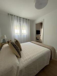 a white bedroom with a large bed with pillows at Apartamentos La Hormiga Deluxe in Adra