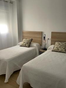 ein Schlafzimmer mit 2 Betten und einem Tisch mit einer Lampe in der Unterkunft Apartamentos La Hormiga Deluxe in Adra