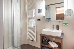 a bathroom with a sink and a shower at Vitalpina Hotel Waldhof in Rablà