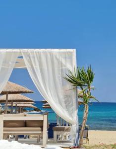 a tent and a palm tree on the beach at Ladario Studios in Sarti